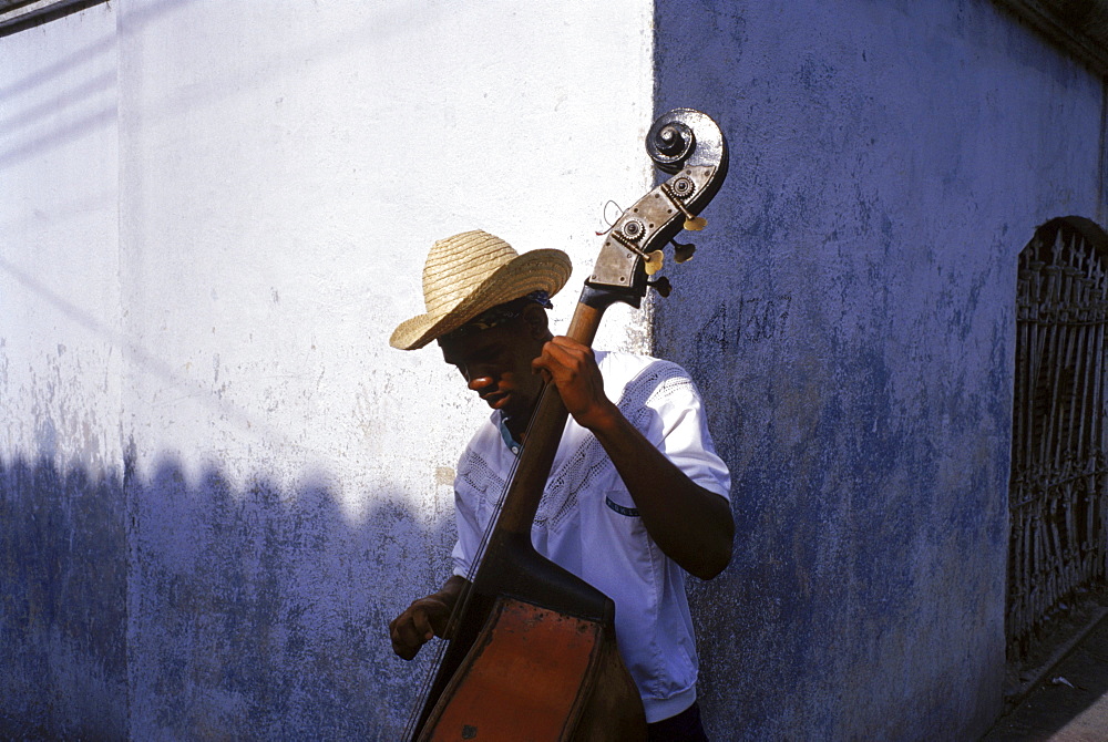 A young musician stops to play some music for tourists and locals as they walk by, hoping to earn some of their change.