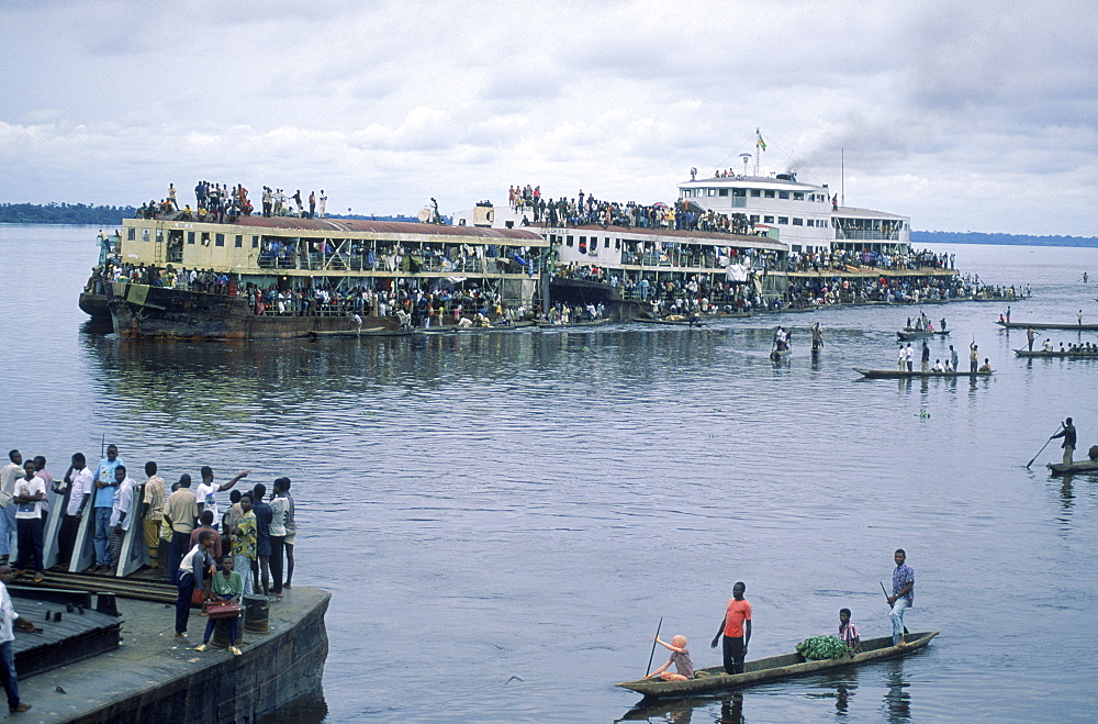 Villagers and pirogues await the arrival of the Col. Ebeya as it pushes its very crowded barges up the Congo River from Kinshasa to Kisingani. . The boat is a moving market for people who live along the river.