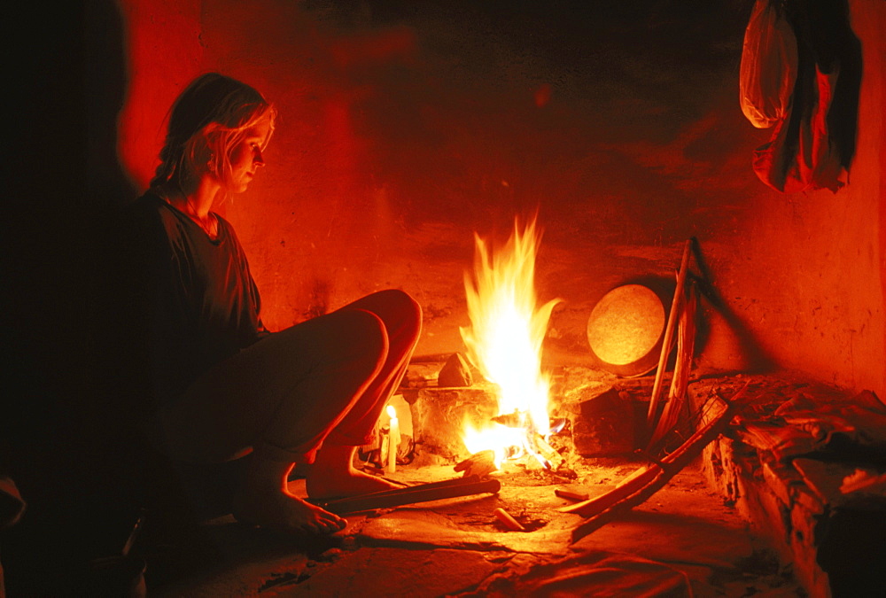 A young woman rests reflectively by a hearth in Almora India