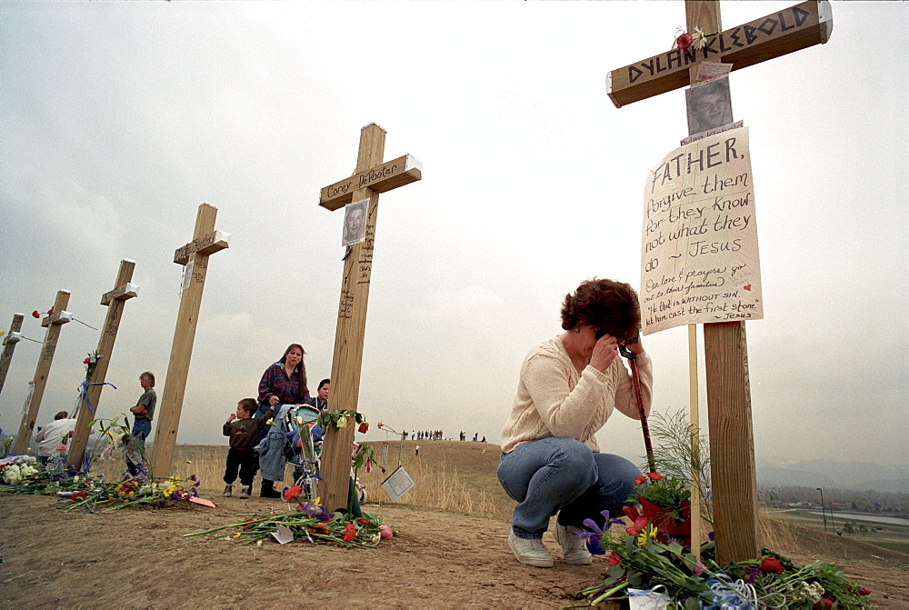 Cindy Fairchild, of Aurora, Colo., prays below a six-foot cross in honor of Columbine shooter Dylan Klebold at Robert F. Clement Park in Littleton. Fifteen identical crosses were planted on a hill in the park, one for each victim of the shootings at Columbine High, including shooters Eric Harris and Dylan Klebold.