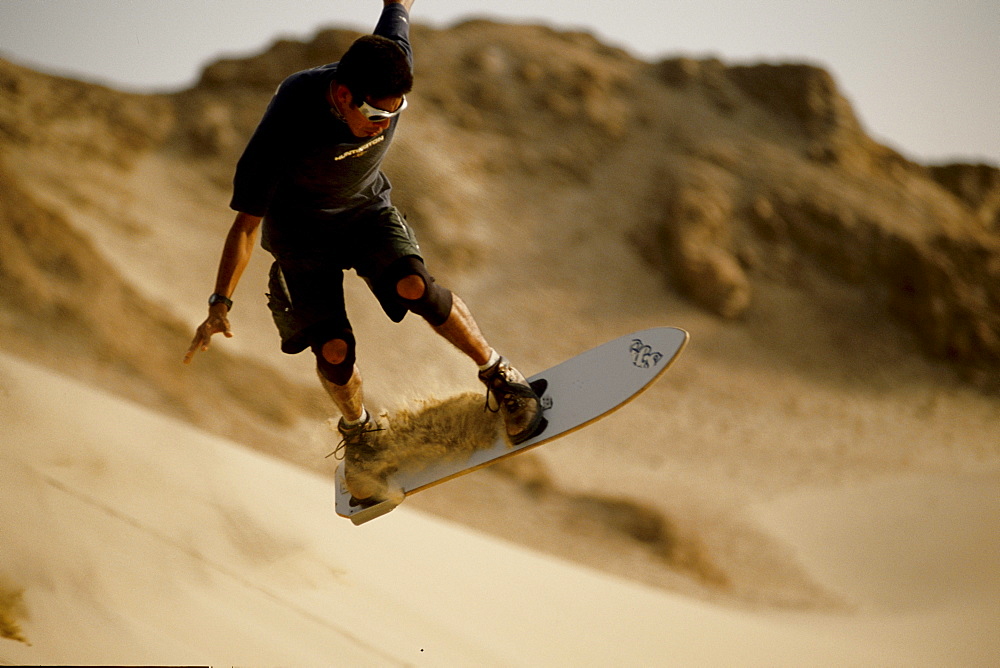 A famous local sandboarder trying to keep his balance 10 feet off the ground in the Ica Desert, Peru on June 25, 2002. Local kids in the Ica Desert, inspired by American snowboard videos, are creating a new sport and riding the highest dunes in the world. (photo by Olivier Renck, Aurora)