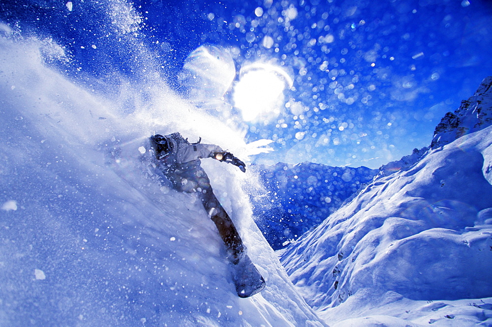 A snowboarder carves an 'in your face turn' while snowboarding on a sunny day in Chamonix, France.