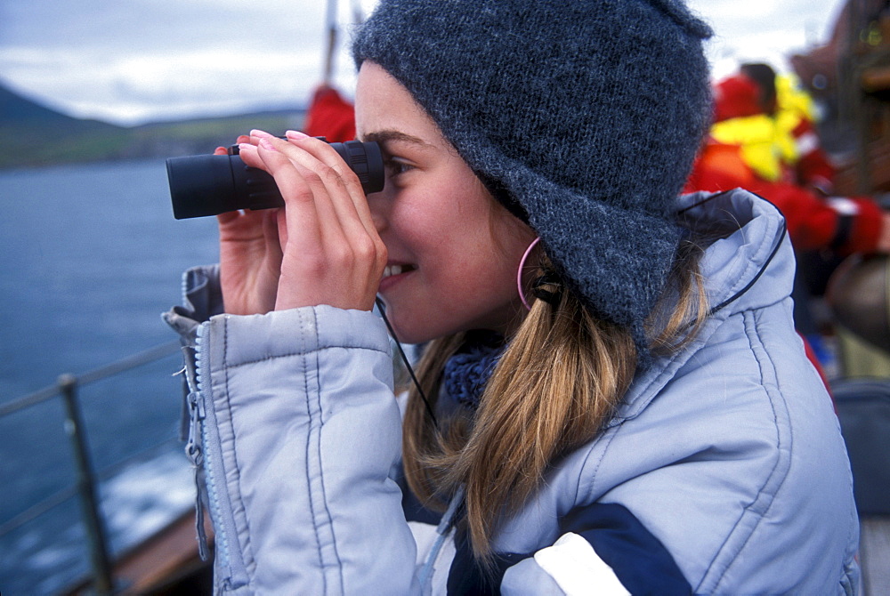 An Icelandic girl looks for whales on a whale watching boat near Husavik, Iceland