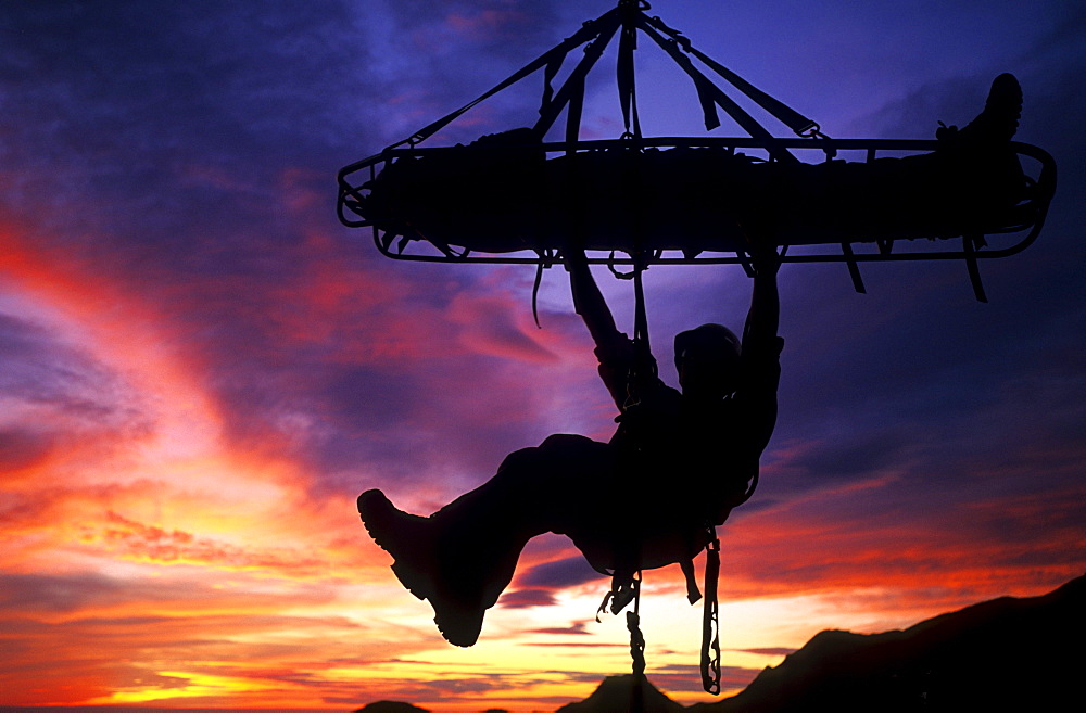 Shannon Black, silhouetted against the sunset sky, tends a Search and Rescue stretcher on the overhanging face of Gibraltar Rock in Santa Barbara, California on January 18, 2003.