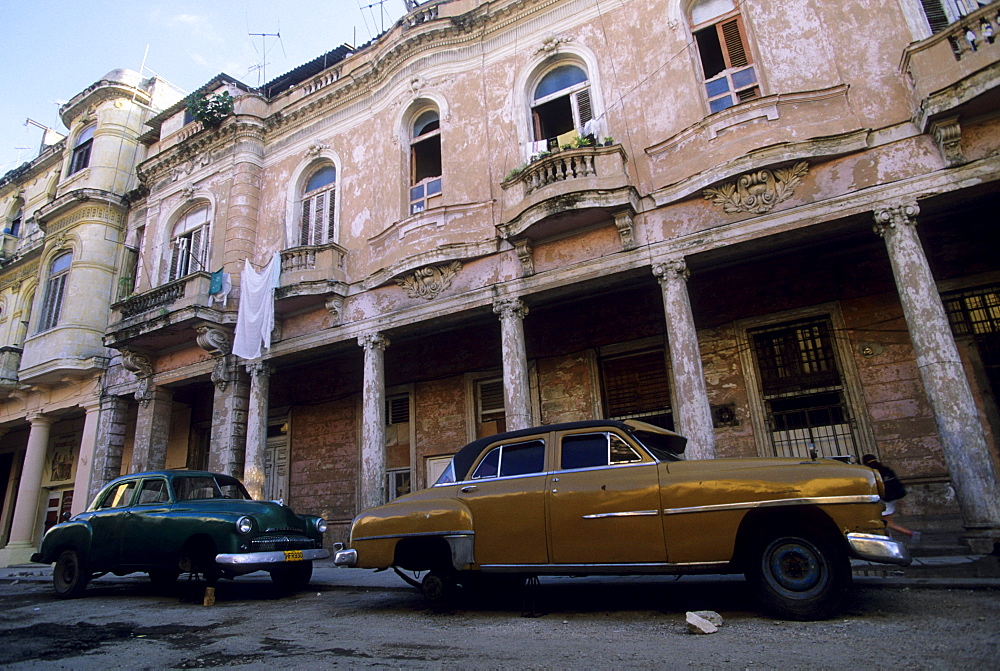 Vintage American cars sit on blocks below a deteriorating building from the Colonial era in Old Havana.  Because of the blockade and economic hardships, cars are a precious possession and many are passed down from generation to generation.