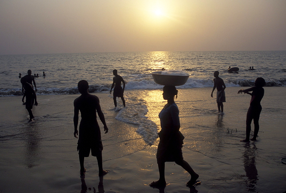 Locals walk and play on the beach at sunset on the Atlantic Coast of Gabon's capital, Libreville.