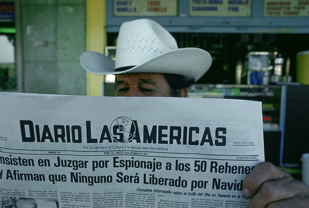 Man reads newspaper, downtown Miami, Florida.