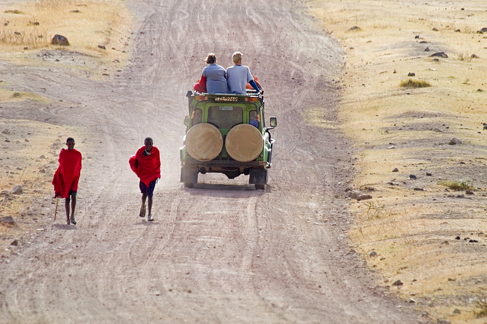 A clash of cultures and centuries: Masai teenagers walk past Western tourists on safari in Ngorngoro National Park, Tanzania.