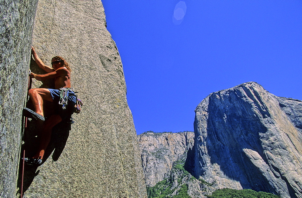 Rock climber Mike Lewis jams up the third pitch of a thin finger crack in Yosemite National Park. El Capitan is in the background.