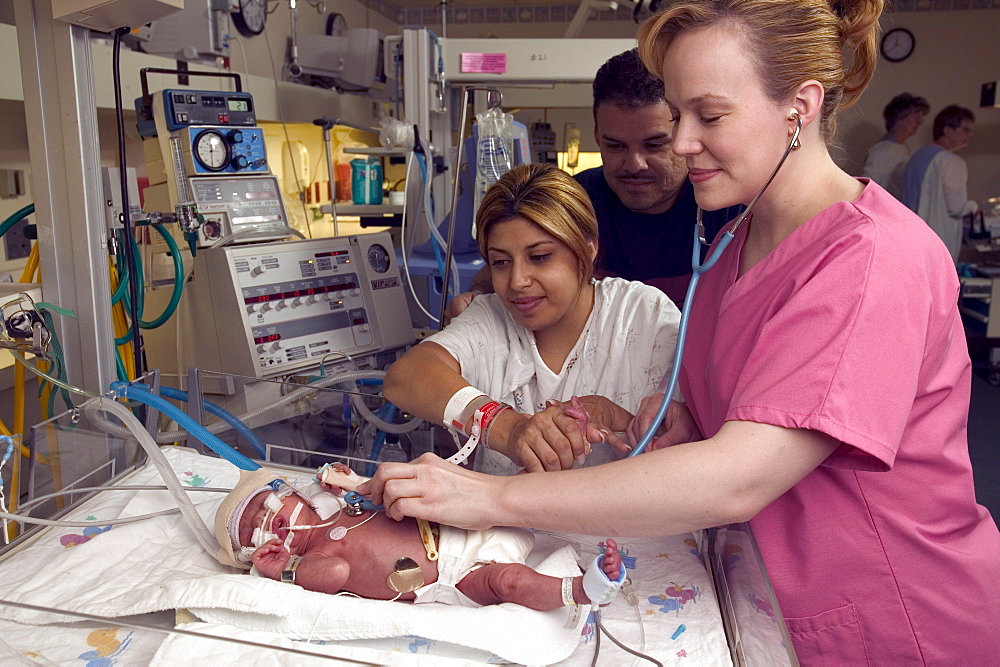 A nurse checks vital signs on a  premature child as it rests.