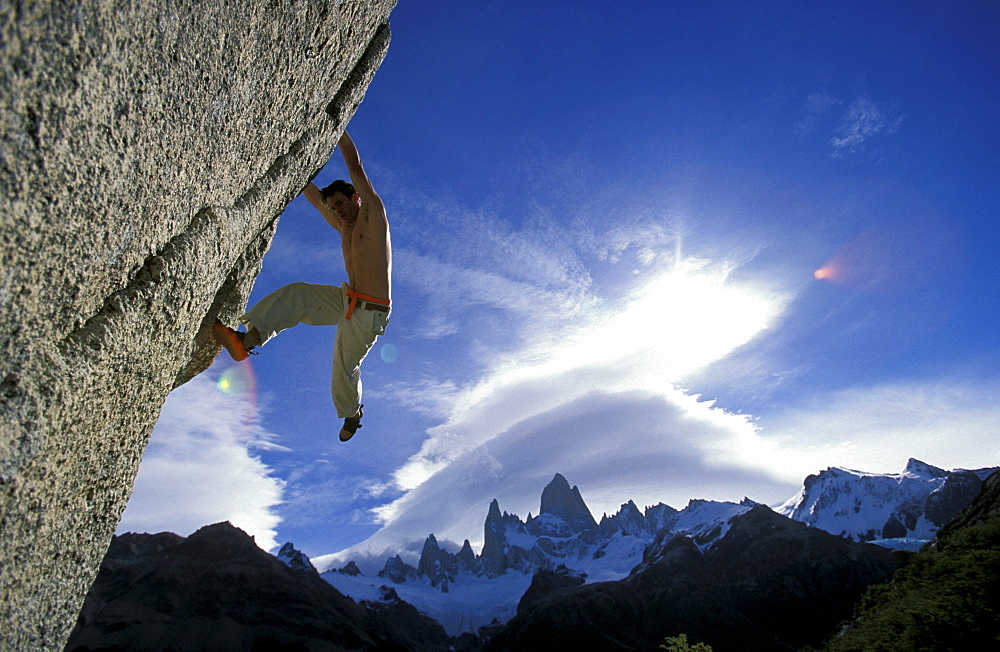 Eric Chabala looks for foot placement on an overhanging bouldering route. Eric is on a bouldering expedition in Patagonia, outside of El Chalten, Argentina. Fitz Roy Peak is in the background.