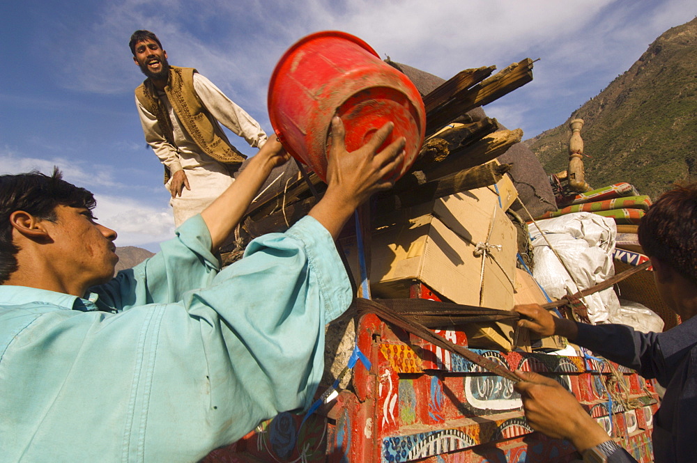 At the Meira tent camp for earthquake survivors, Pashtun men load their family's possessions onto a tractor trailer as they prepare to leave the camp, where they have spent the winter, the Allai  Valley, Northwest Frontier Province, Pakistan.