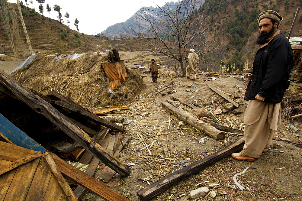 Men from the village of Gangwal, which was devastated in the 2005 earthquake, show makeshift shelters that villagers constructed themselves after the quake, in the upper Allai Valley, NWFP, Pakistan.  Most of the villagers fled to tent camps at lower elevations to spend the winter, leaving just a handful of families to look after livestock and possessions. The people of this remote area are  Pashtun and until the earthquake, neither the government nor the military had much presence or influence in the region.