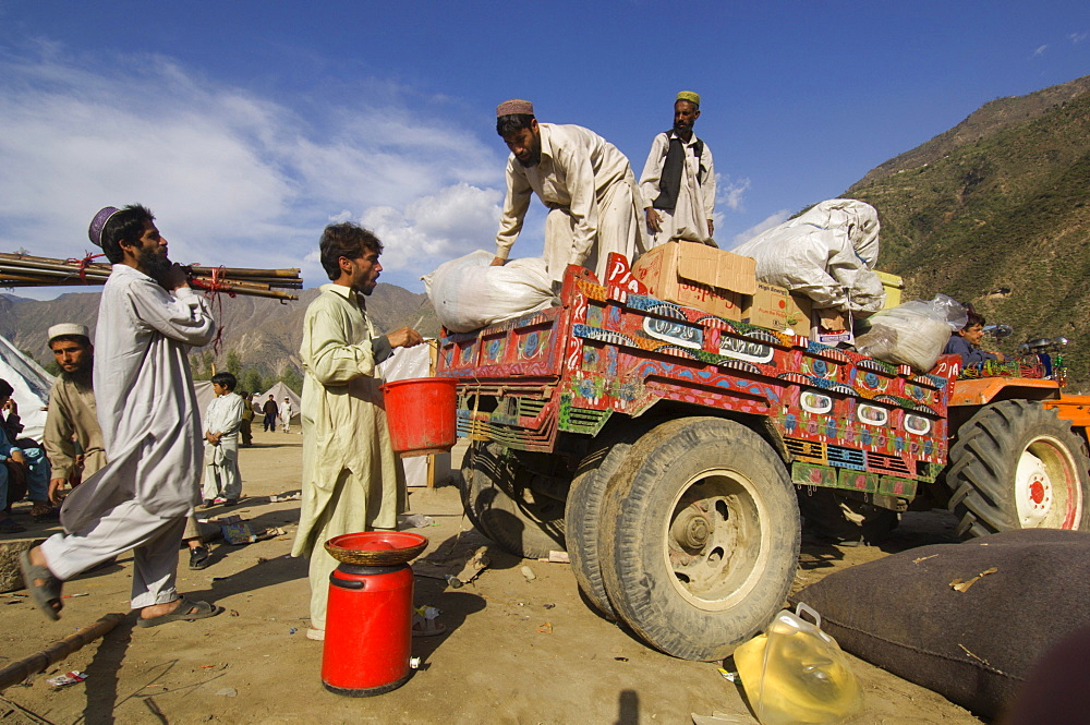 At the Meira tent camp for earthquake survivors, Pashtun men load their family's possessions onto a tractor trailer as they prepare to leave the camp, Allai  Valley, NWFP, Pakistan.