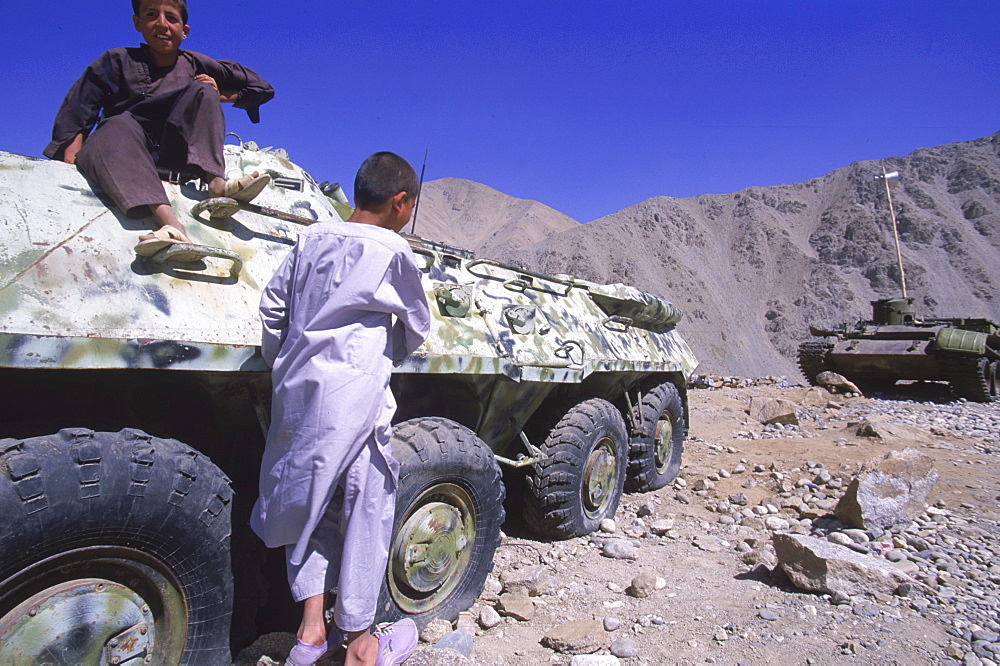 Children play on a tank in the Panjshir Valley while waiting for ceremonies to begin in honor the one year anniversary of the assasination of Ahmad Shah Masood, September 9, 2002. The Panjshir Valley was a stronghold for the Tajik people and the famous commander Masood in their struggle first against the Soviets and then against the Taliban.  The valley and villages of the Panjshir were subjected to heavy bombing and destruction during the Afghan-Soviet war, but was never fully occupied.  Now it is the heartland for the powerful Tajik ethnic group, the second largest in Afghanistan, who came to partial power after the fall of the Taliban.