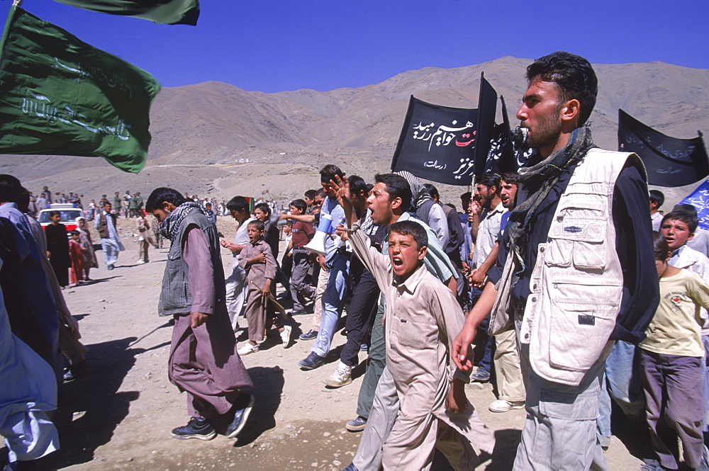 Schoolboys chant and carry banners  to the shrine in the Panjshir Valley of the famous Tajik commander, Ahmad Shah Masood, on the one year anniversary of his assasination, September 9 2002.  Masood was a revered mujahedin leader who also was one of the leaders of the Northern Alliance which opposed the Taliban and helped the US Military in their defeat.  Masood was assasinated by what are thought to be Al Queda operatives on Sept. 9, 2001.  A shrine has been erected in the Panjshir  Valley  from where he led much of his resistance to both the Soviet and Taliban forces, to honor this latest of Afghan war heros.