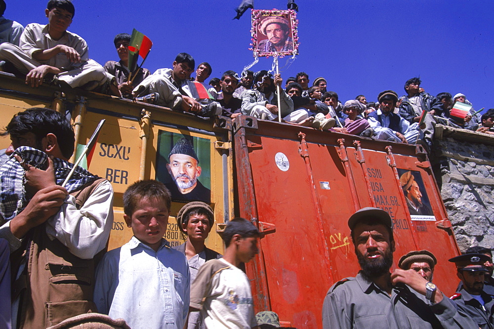 Crowds of boys and men, holding  posters of Ahmad Shah Masood and Afghan president Hamid Karzai, line the roofs of buildings during a ceremony in the Panjshir Valley  on the one year anniversary of Masoods assasination, September 9, 2002. Thousands  of people from all over Afghanistan and the world, including many important dignitaries, arrived in the Panjshir Valley for ceremonies honoring  Masood, a revered mujahedin leader who also was one of the leaders of the Northern Alliance which opposed the Taliban and helped the US Military in their defeat.  Masood was assasinated by what are thought to be Al Queda operatives on Sept. 9, 2001.  The shrine to honor this latest of Afghan war heros was built in the Panjshir  Valley  as that is from where Masood led much popular resistance against both the Soviets and the Taliban forces.