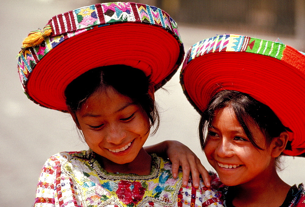 Two Mayan girls laughing in traditional clothes.