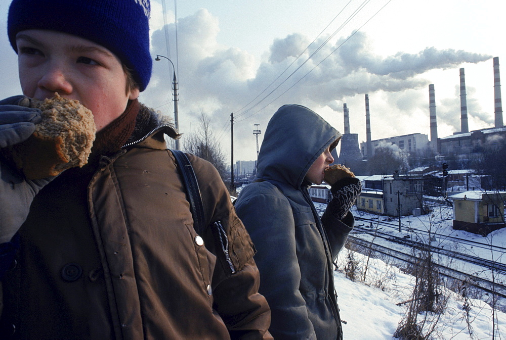 Children eating bread with a Moscow power plant in the background.