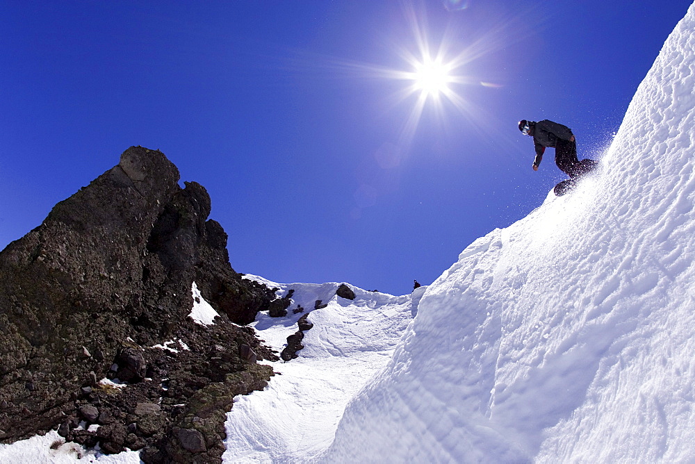 Young man dropping into couloir at Kirkwood ski resort near Lake Tahoe, CA.