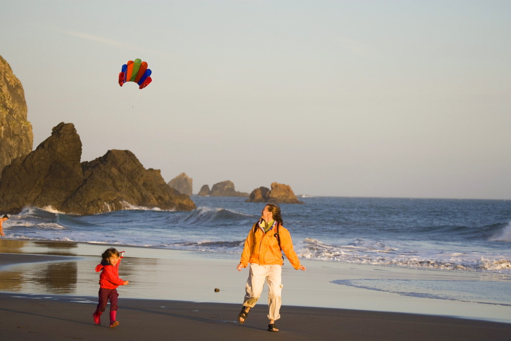 Young mother and daughter fly kite on beach, Harris Beach State Park, Oregon, USA