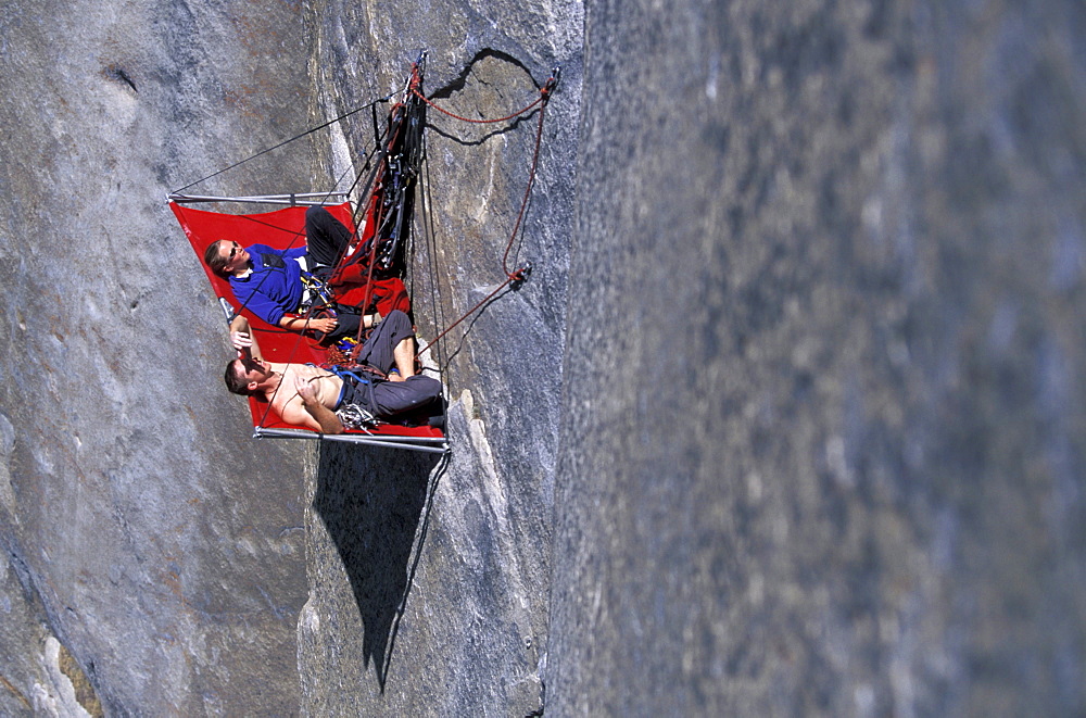 Beth Rodden and Tommy Callwell hang out on a rock ledge so Tommy can rest from rock climbing Dihedral wall, a multi pitch route on El Capitan in Yosemite National Park, California.