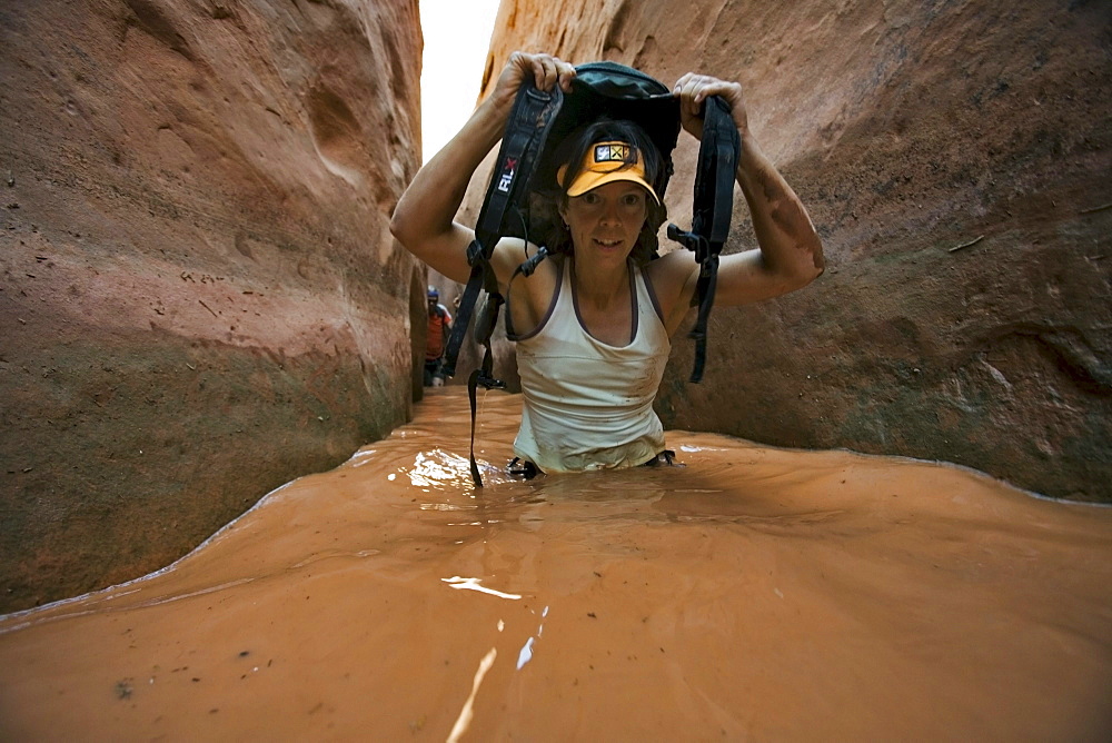 A woman wading through water in narrow canyon, Utah.