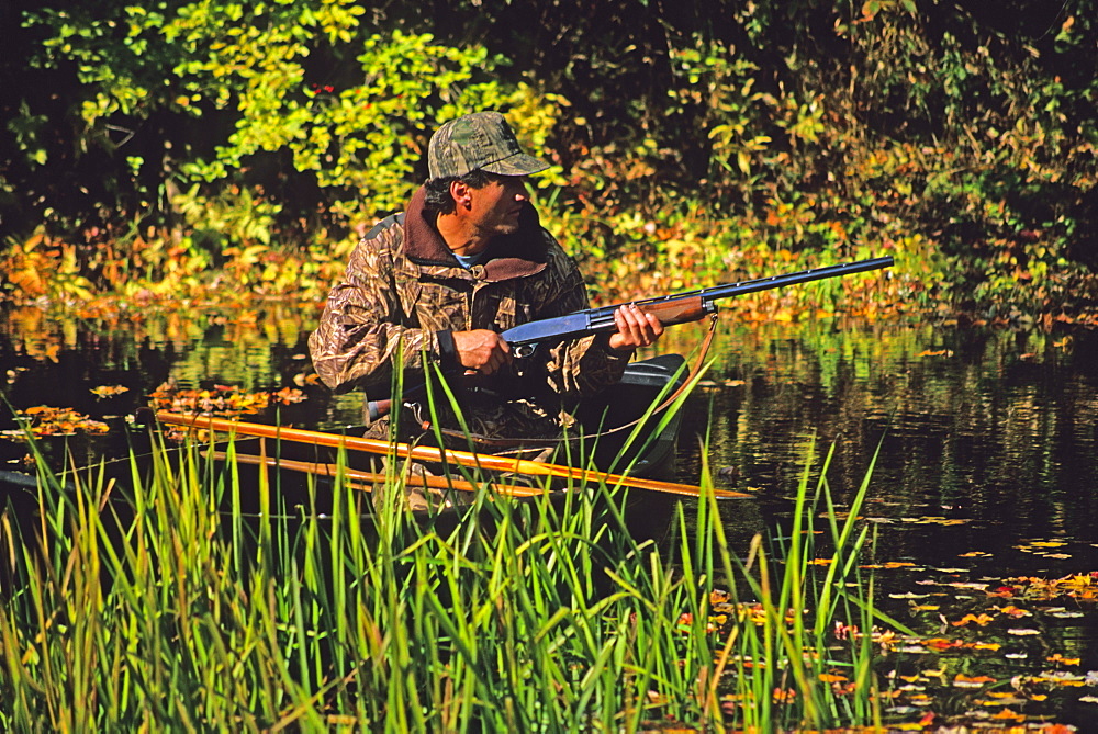 A duck hunter watches for game from his canoe on the Lamprey River, New Hampshire.