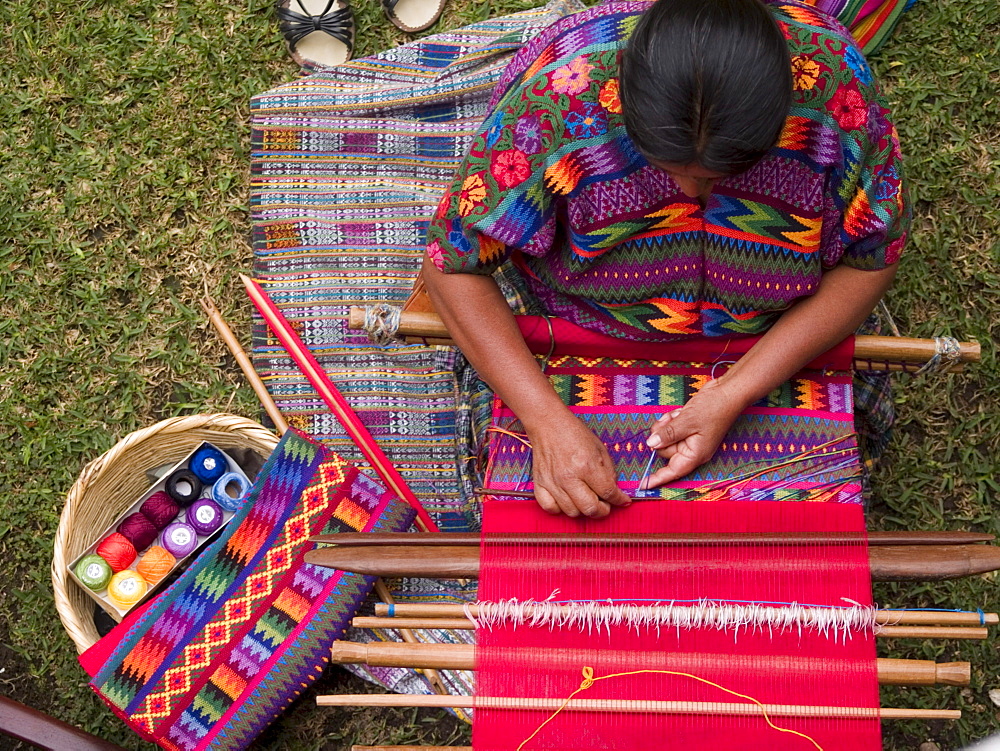 A woman from an indigenous community in Guatemala weaving while wearing an indigenous dress at work in Antigua, Guatemala.