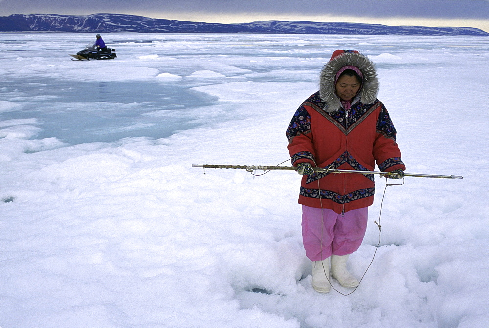 Mrs. Muckpa waits by a hole for a seal to come up to take a breath.