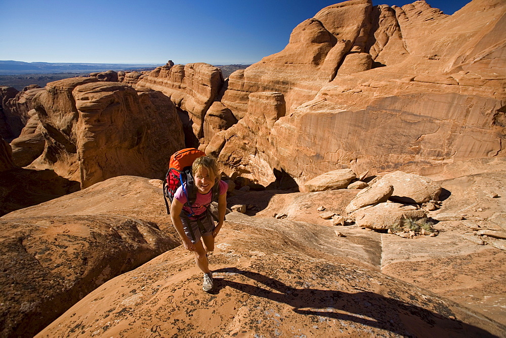 A woman hiking in a rocky slickrock area, Arches National Park, Moab, Utah.