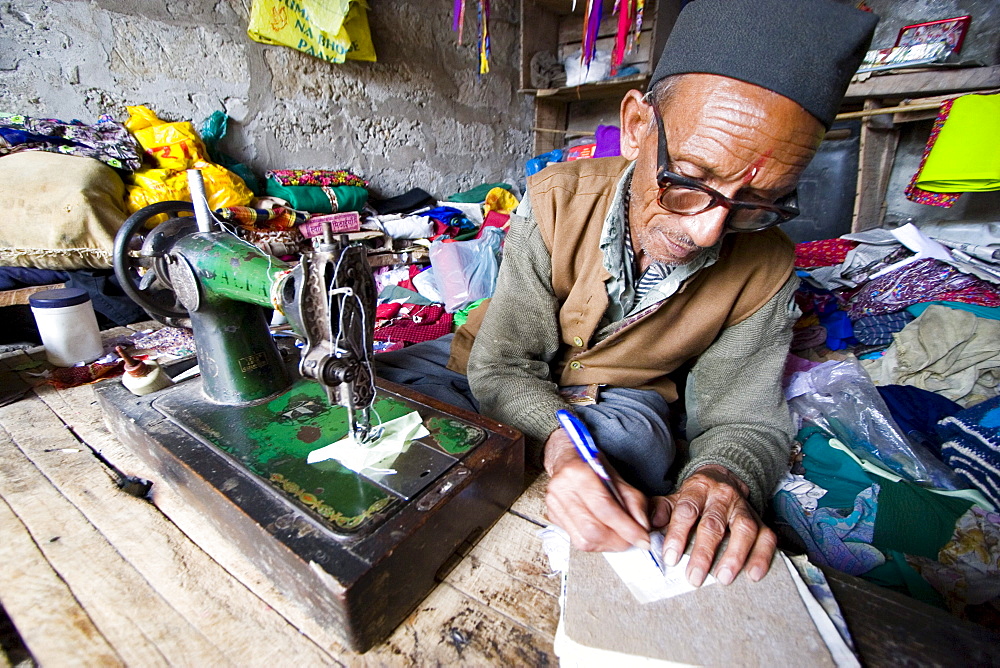 Man sewing goods in small village, India