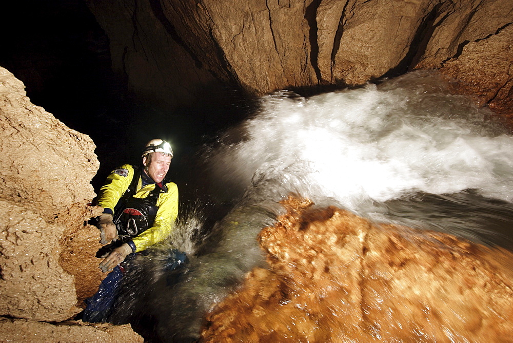 A cave explorer reaches the top of a waterfall underground in New Britain