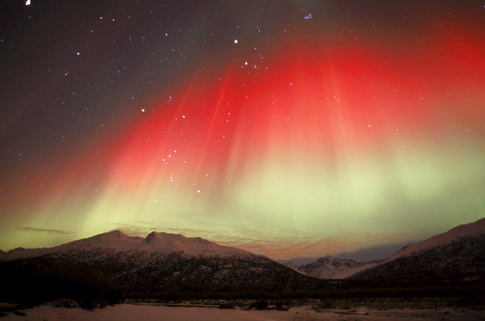 The aurora borealis (northern lights) shines with a rare, red and green hue above the Chugach Mountains in Alaska's Knik River Valley.