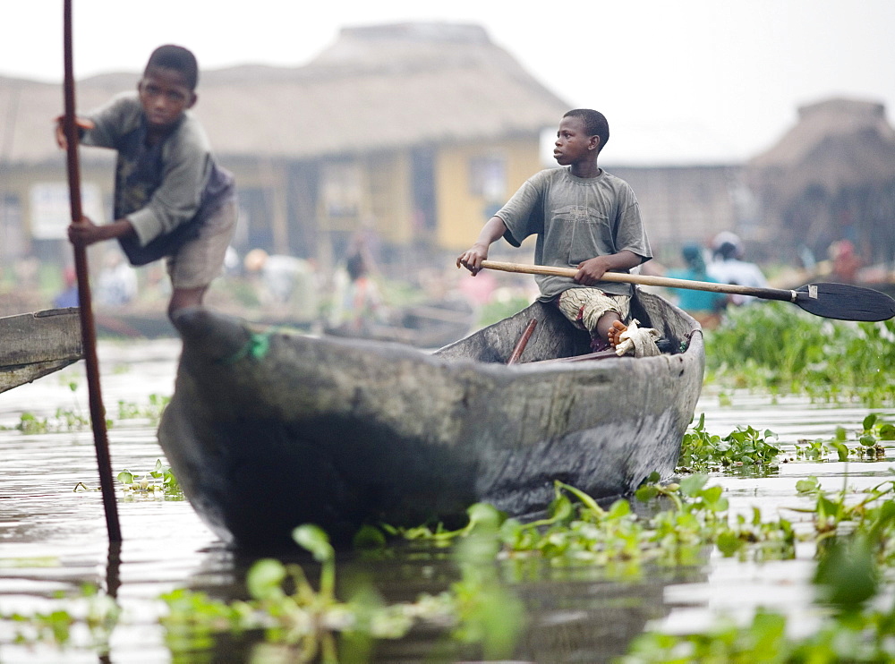 Young boys canoe through the village of Ganvie