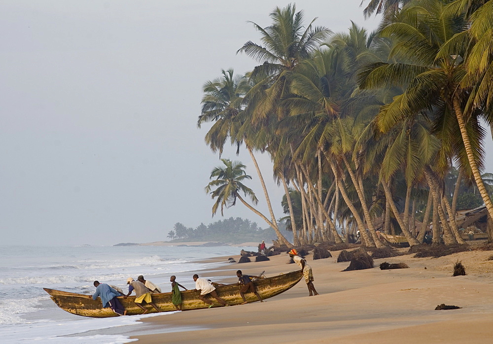 Fishermen pushing large canoe