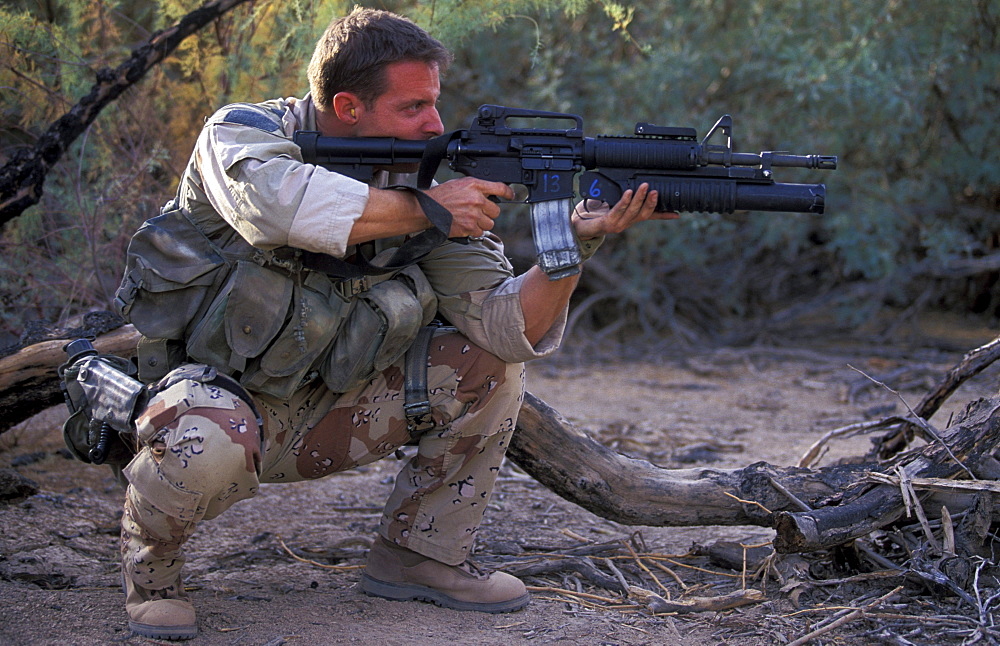 Man in camouflage with a gun training in the woods near San Diego, California.
