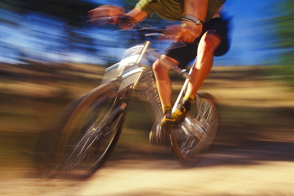 A Mt. biker speeds by on a mountain trail.