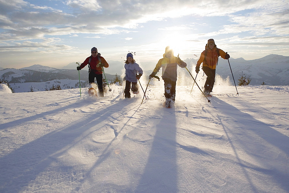 Four people snowshoeing in France. (back-lit)