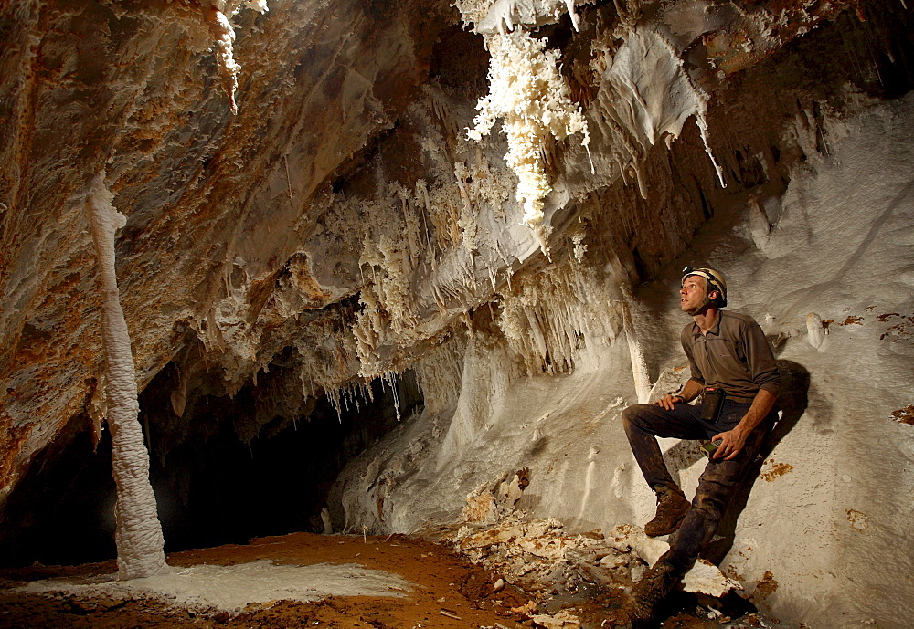 A British cave explorer casually admires the highly decorative formations in this particular passage, in Whiterock (cave). Deep