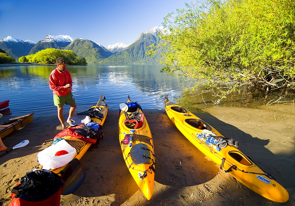 A stands next to kayaking gear in Lago Yelcho, Chile.