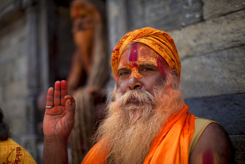 A Hindu priest, a sadhu and esthetic, with body paint poses in a Kathmandu, Nepal temple.