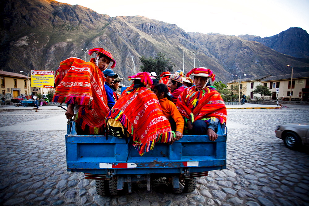 OLLANTAYTAMBO, SACRED VALLEY, PERU. A group of men dressed in traditional clothing in the back of a pickup truck in a  small town.