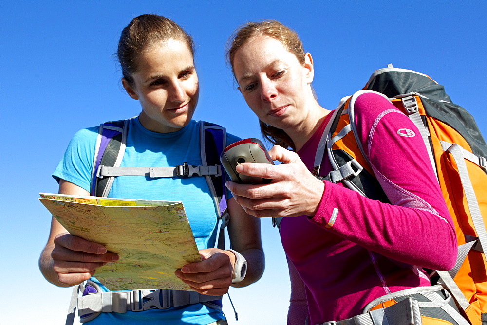 Katrin Schneider and Susann Scheller checking a handheld GPS device while hiking on an ocean trail between Gansbaai and De Kelders. South Africa.