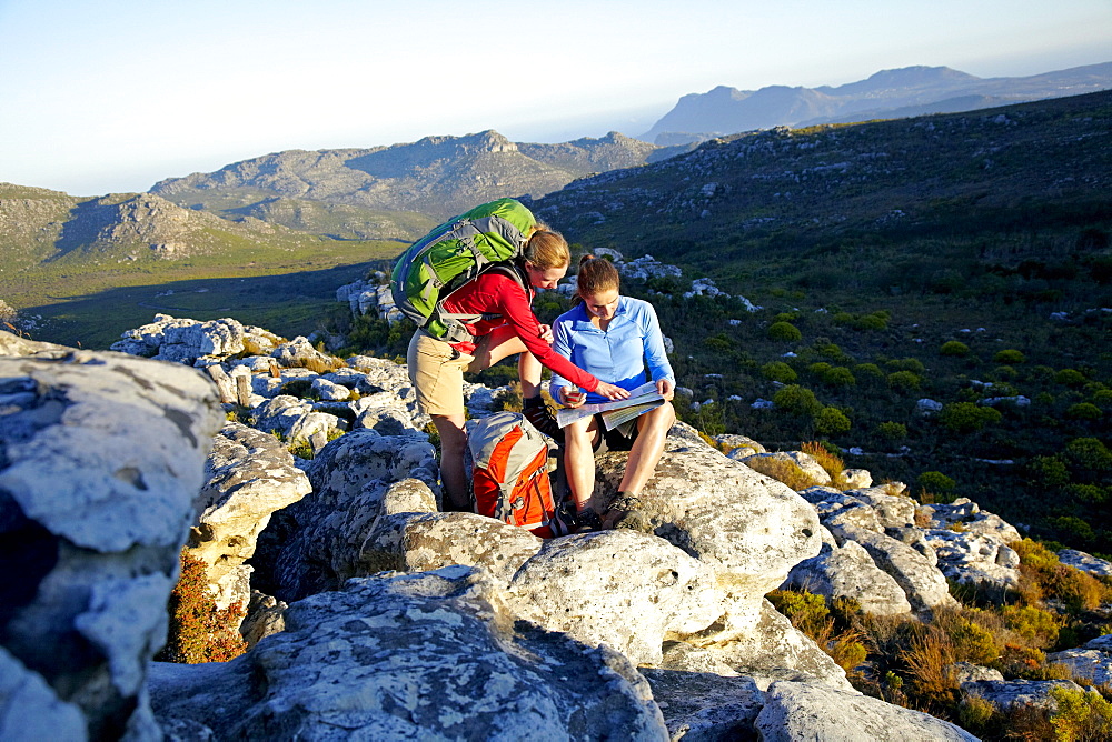 Katrin Schneider and Susann Scheller checking a GPS and a hiking map while hiking on the Hoerikwaggo Trail from Cape Point to Table Mountain in Cape Town. South Africa.