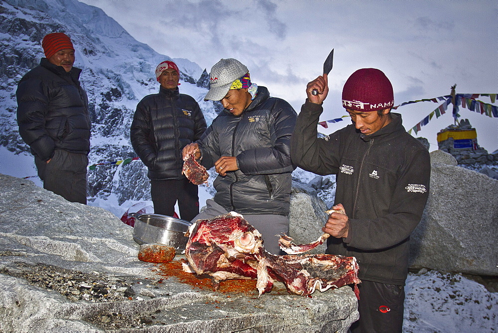 Two cooks for Jagged Globe Everest Expedition prepares Yak meat at Everest Base Camp while two sherpas watch