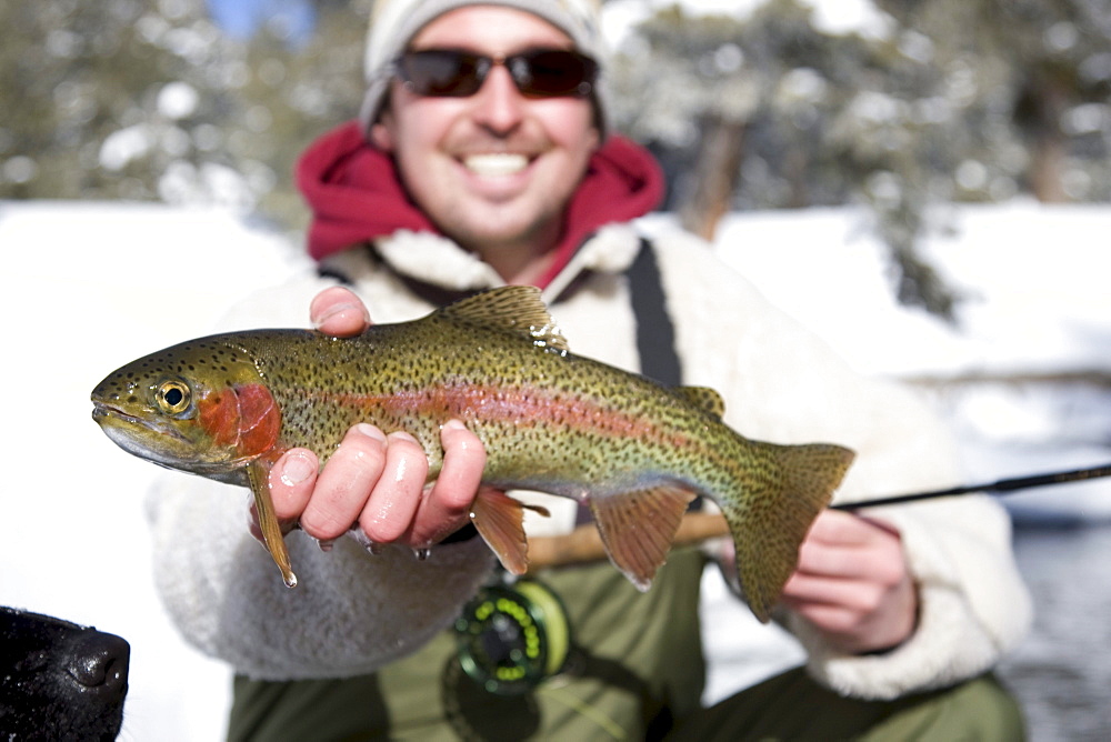 A man out fly fishing on a winter day.