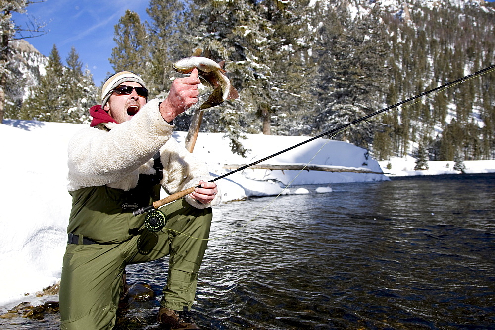 A man out fly fishing on a winter day.