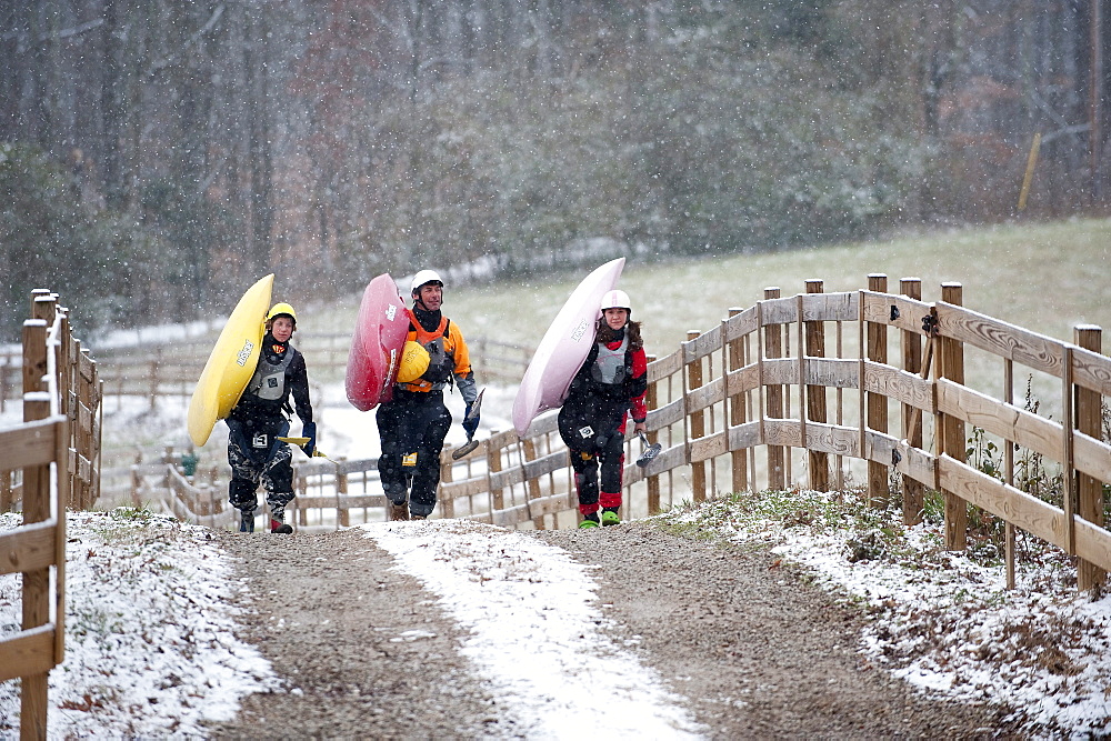 Three kayakers transport their kayaks in Tennessee.