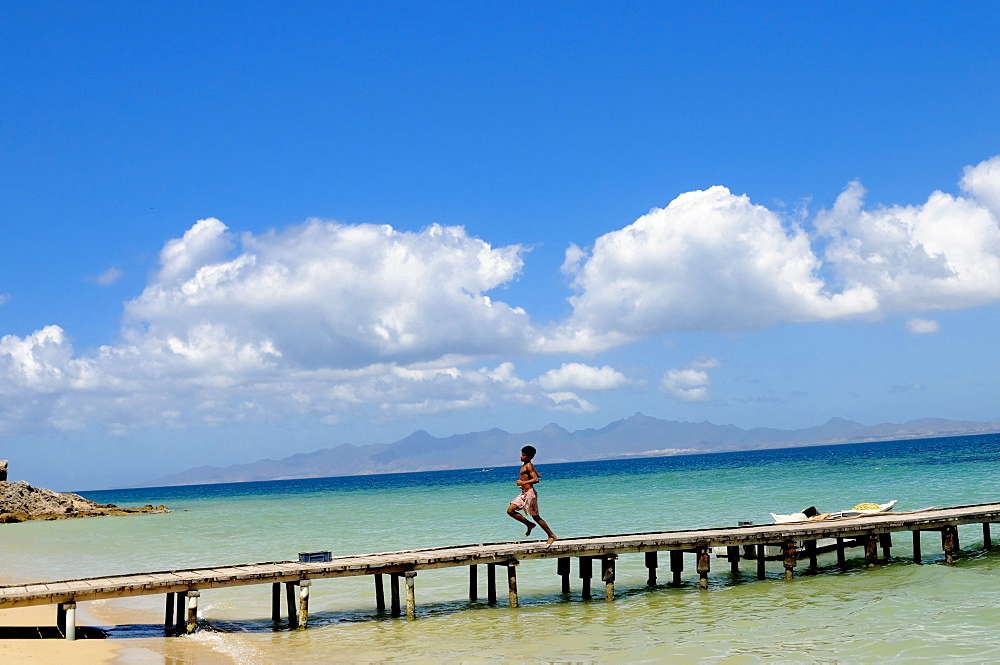 Young boy runs down dock on the Caribbean Island of Cubagua in Venezuela.